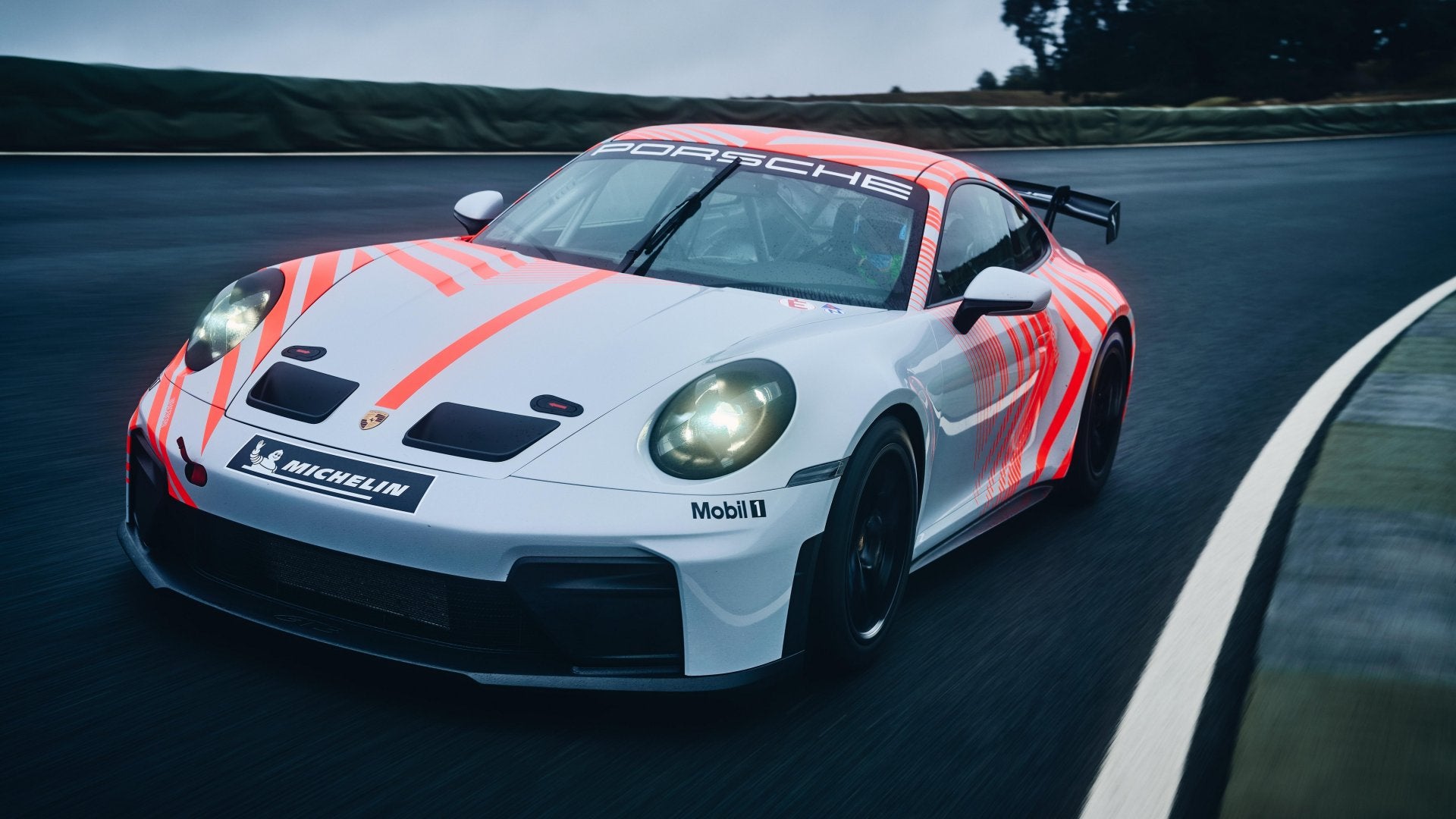 Porsche 911 Challenge race car driving on a circuit, viewed from the front